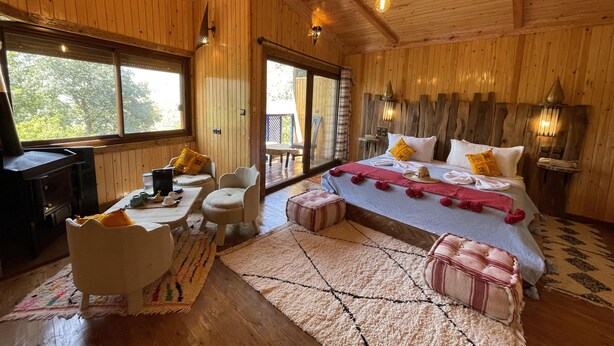 Un dormitorio de cabaña de madera con cama, zona de estar y escritorio.