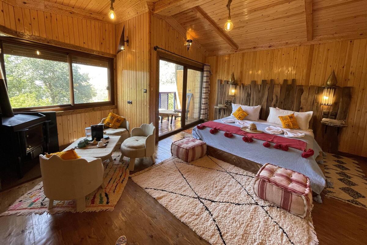 Quarto de cabana de madeira com cama, área de estar e escrivaninha.