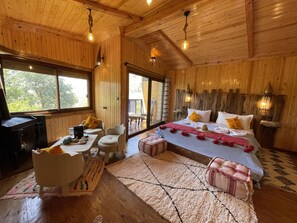 Une chambre dans une cabane en bois, comprenant un lit, un coin salon et un bureau.