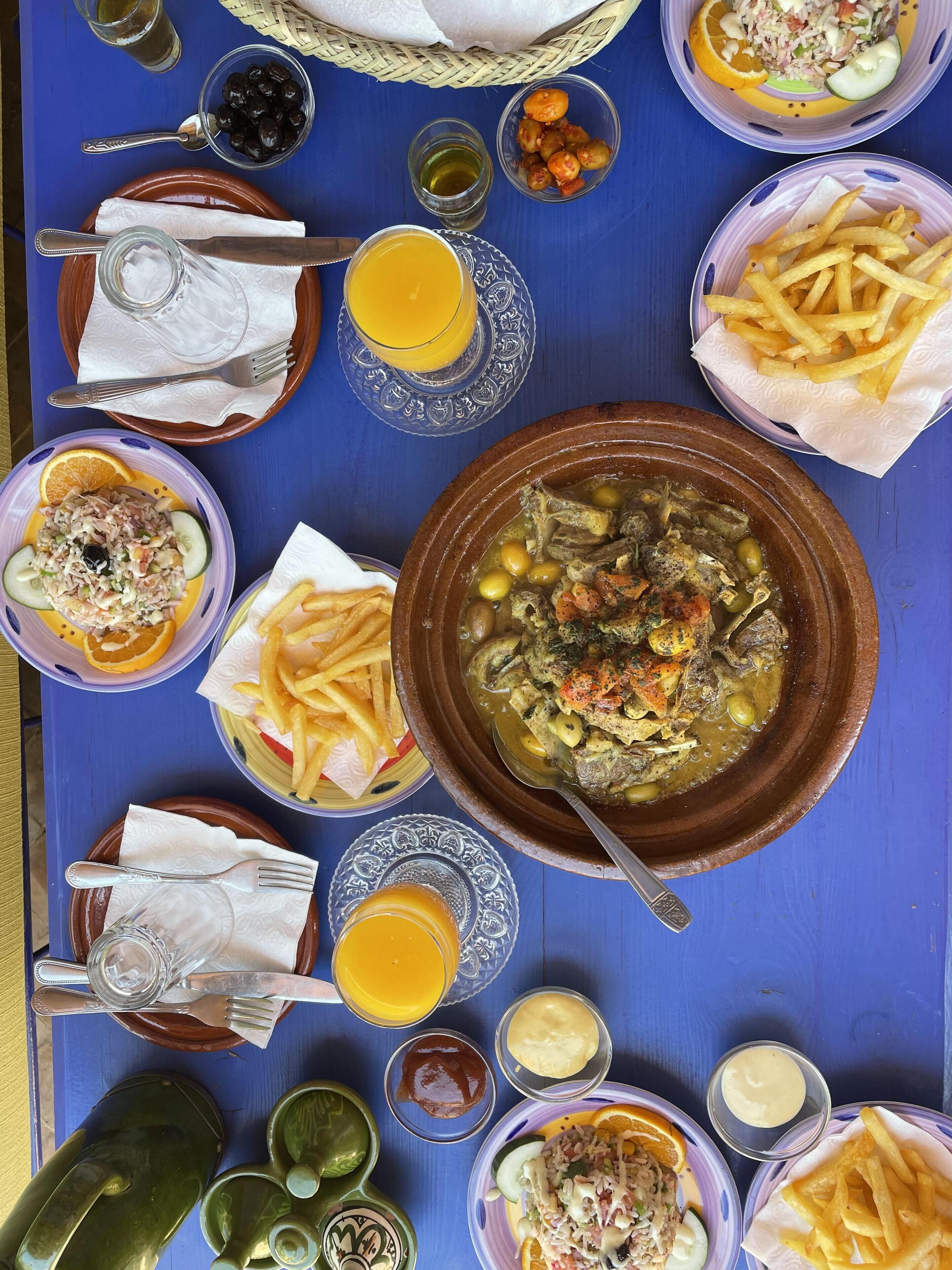 A table with various dishes including a large bowl of stew, French fries, and a salad.