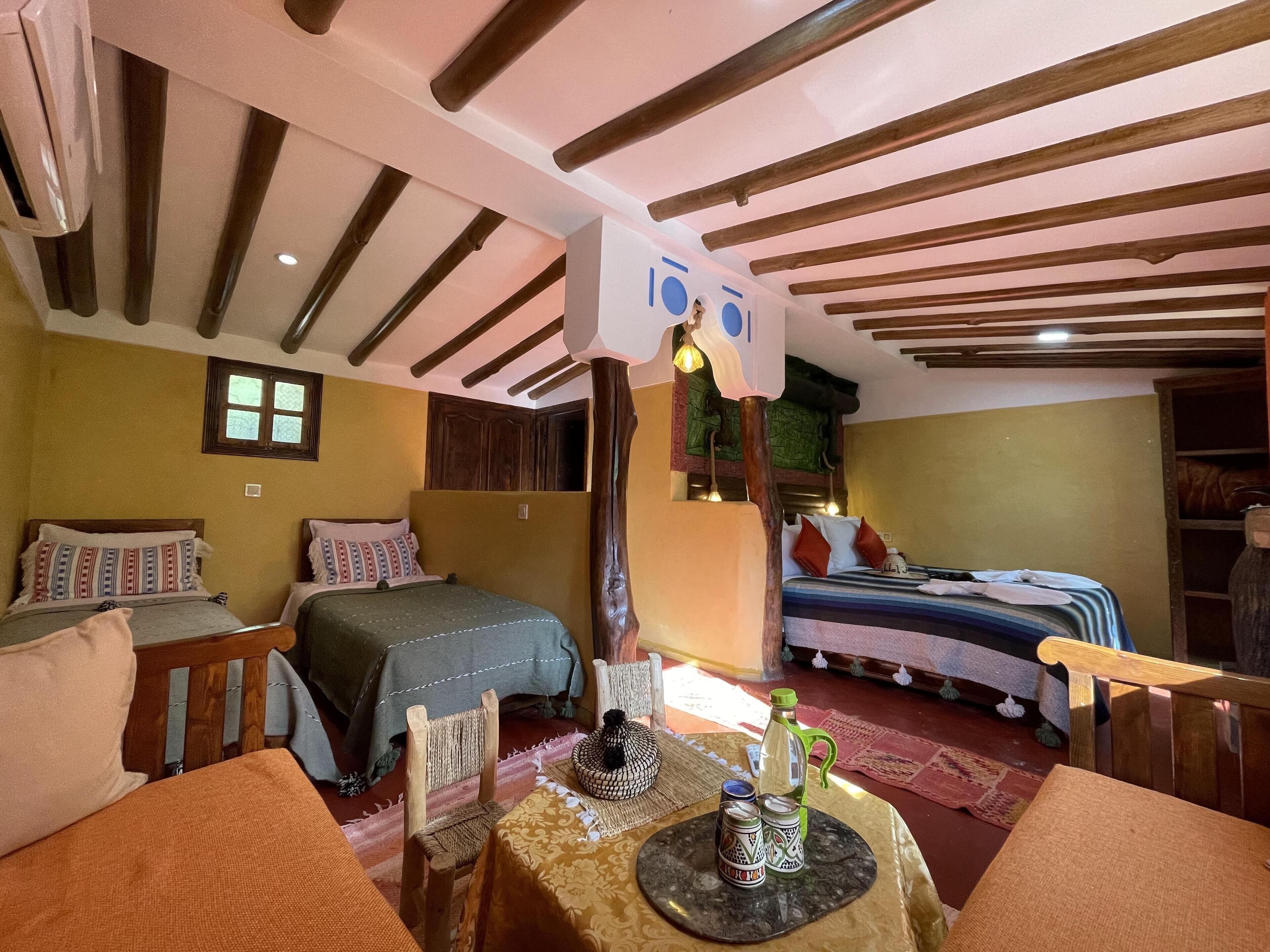 Habitació acollidora amb dos llits, un sostre de fusta i una taula petita amb saleperes i pebreteres.