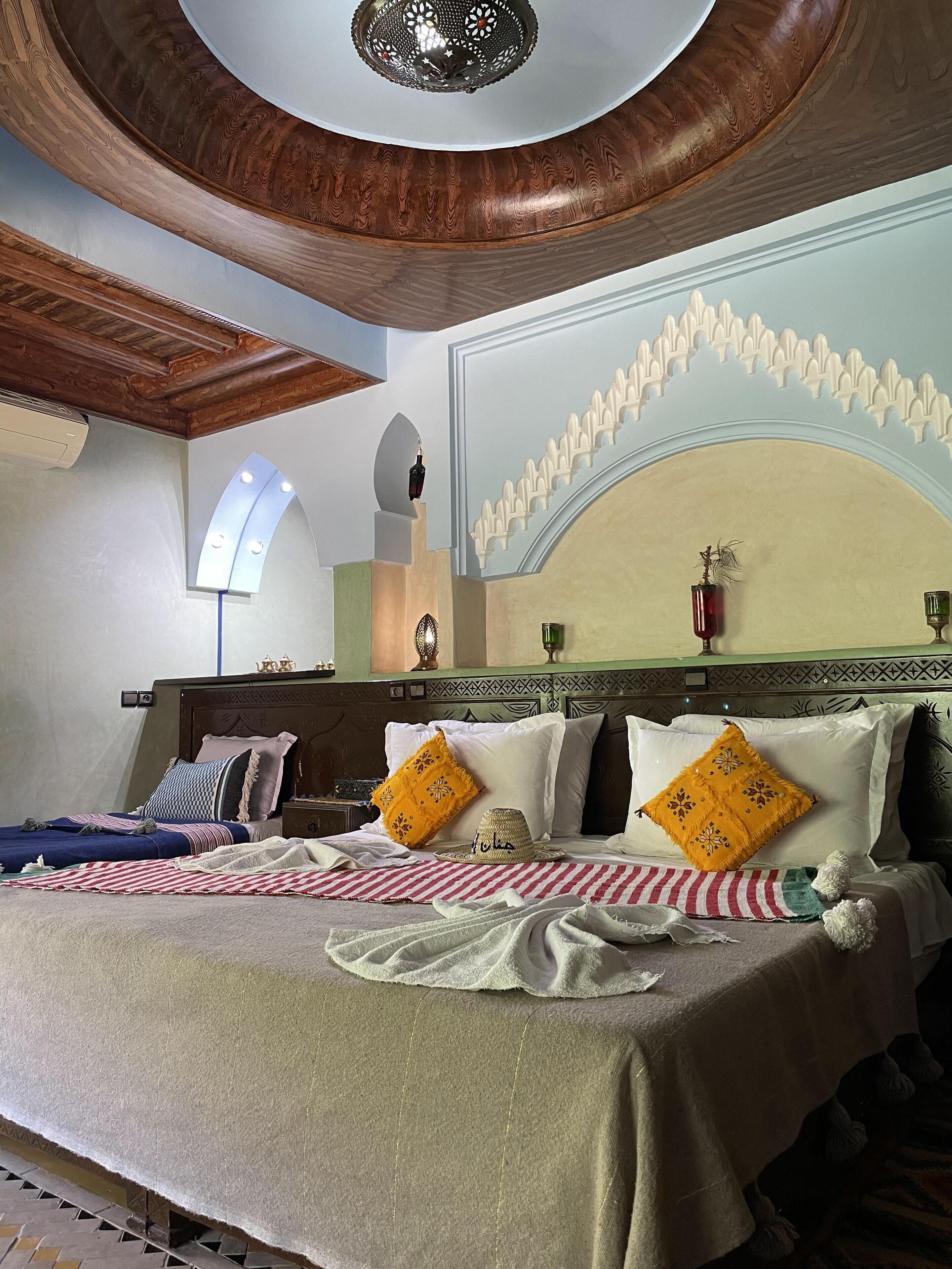 Un dormitorio con una cama grande, un techo decorativo y una pared con arco.