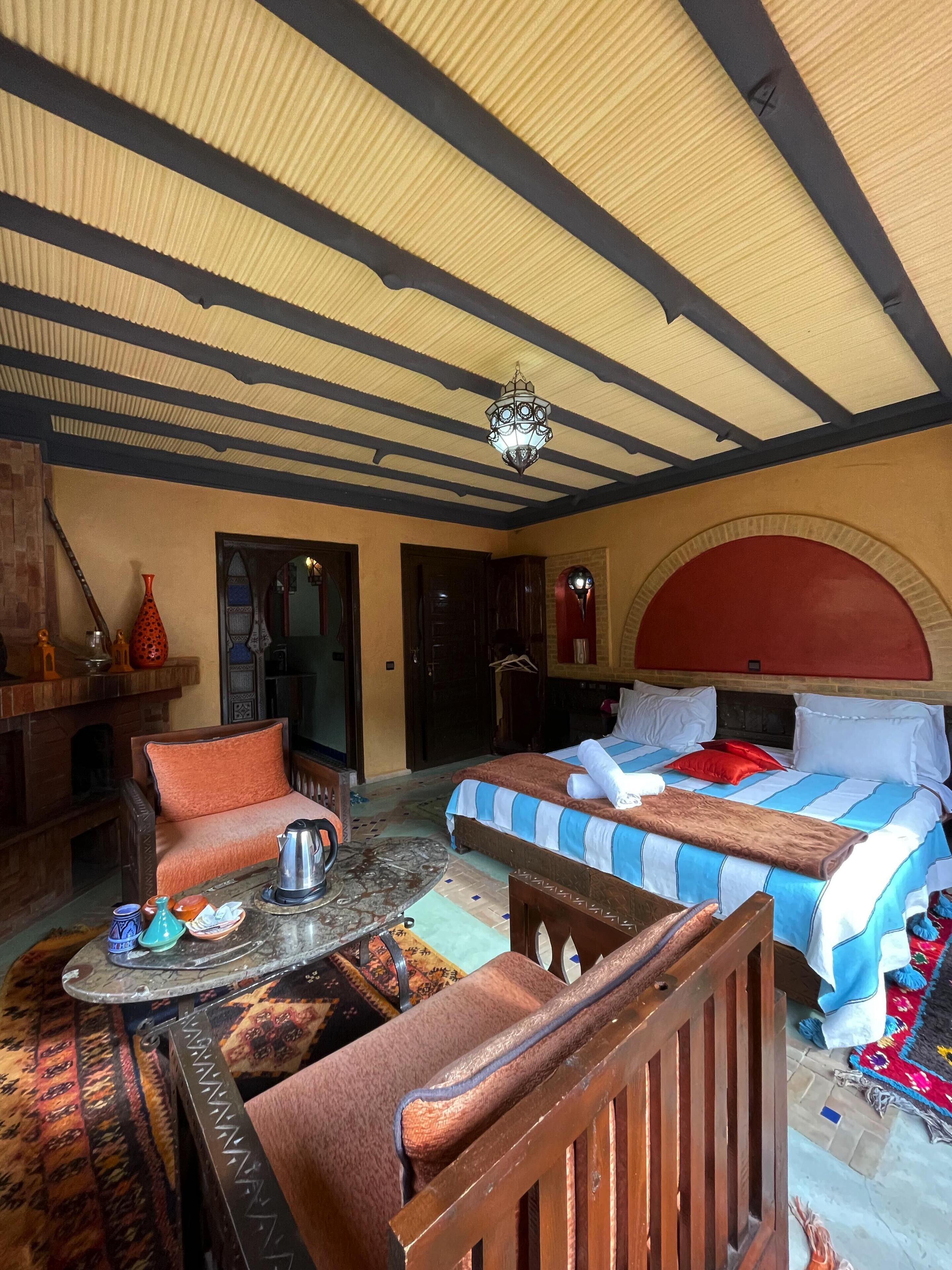 A room with a bed, a sofa, a table, and a hanging light fixture.