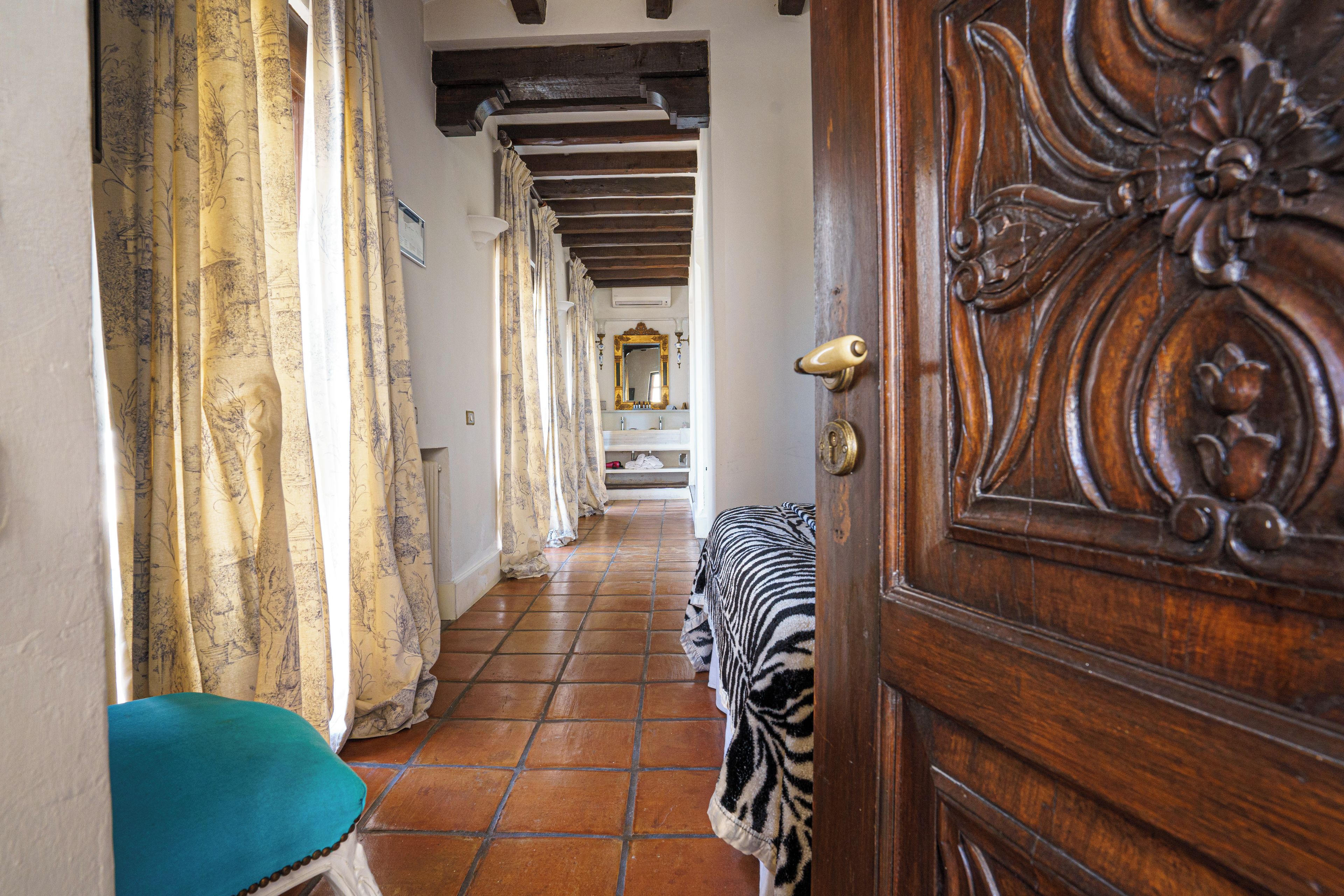 A hallway with a wooden door, a bench, and a tiled floor.