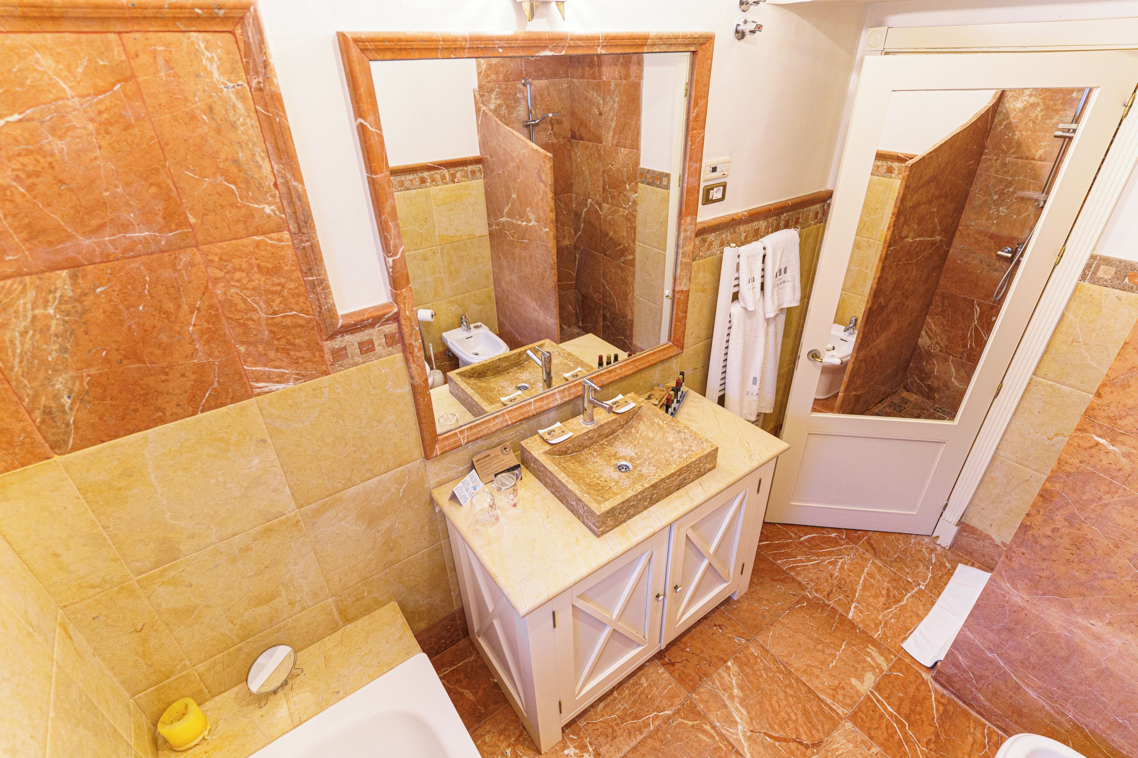 Un baño con lavamanos de mármol, un espejo, una bañera y zona de ducha.
