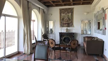Une pièce spacieuse avec un plafond haut, une cheminée et un grand miroir.