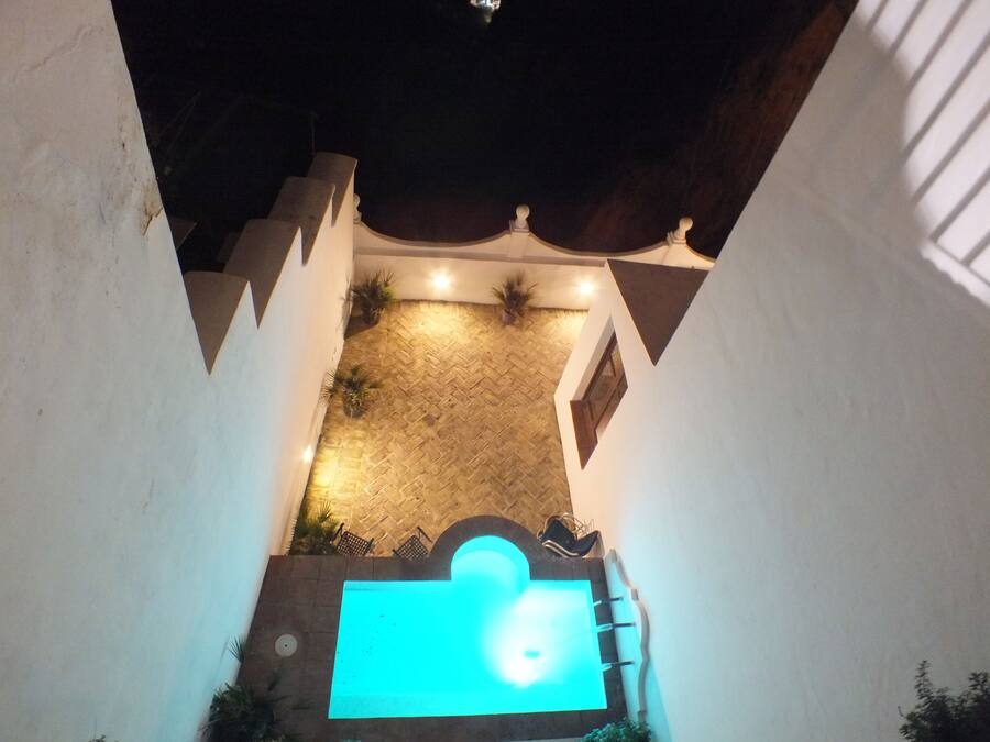 A courtyard with a swimming pool, potted plants, and a tiled floor.