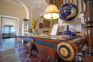 Um hall de entrada com balcão de recepção, um globo, uma luminária e vista para o exterior.