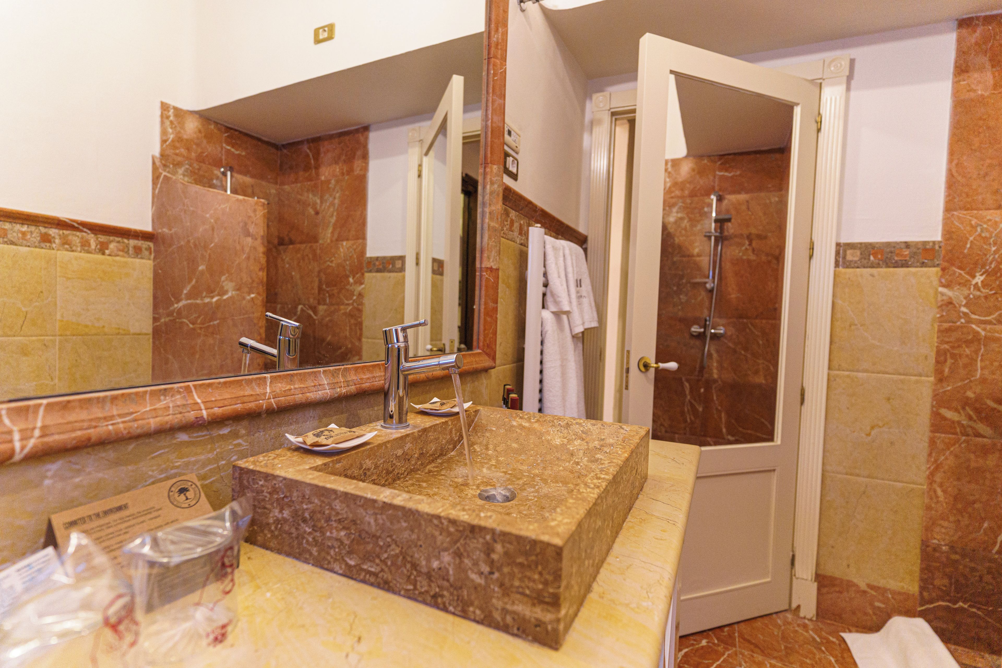 A bathroom with a marble sink, a mirror, a towel rack, and a shower area.