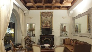 Un salón tradicional con chimenea, muebles ornamentados y un tapiz grande.
