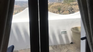 Habitación con vista a un paisaje montañoso a través de una ventana con cortinas.
