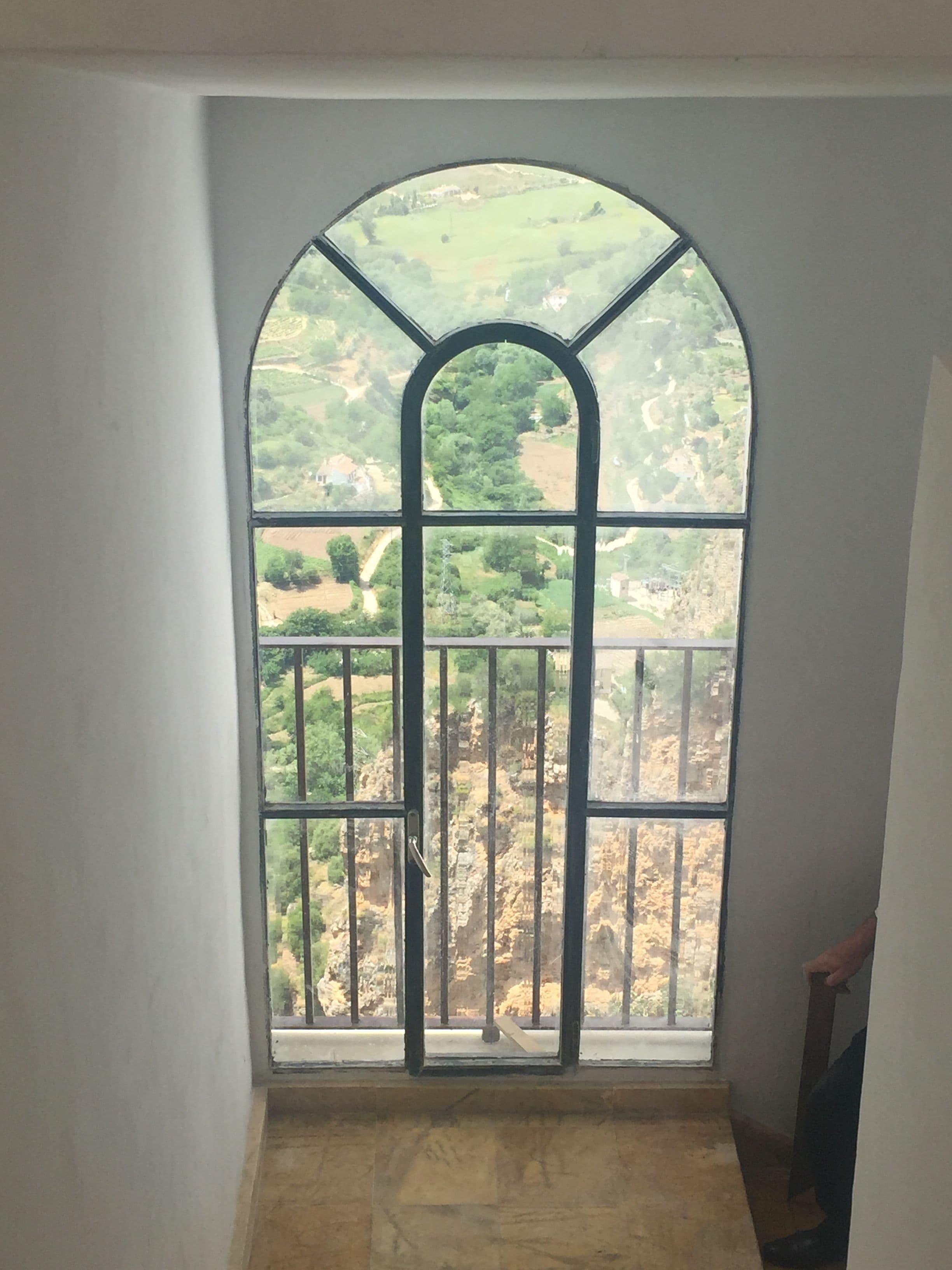 Ein Zimmer mit einem großen Bogenfenster mit Blick auf eine ländliche Gegend.