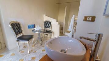 Une salle de bain avec un grand lavabo, deux chaises, une petite table et un porte-serviettes.