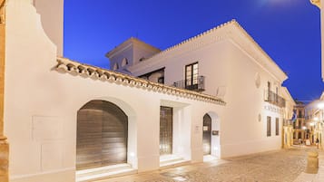 A historic building with a cobblestone street, white walls, and a balcony with wrought iron railings.