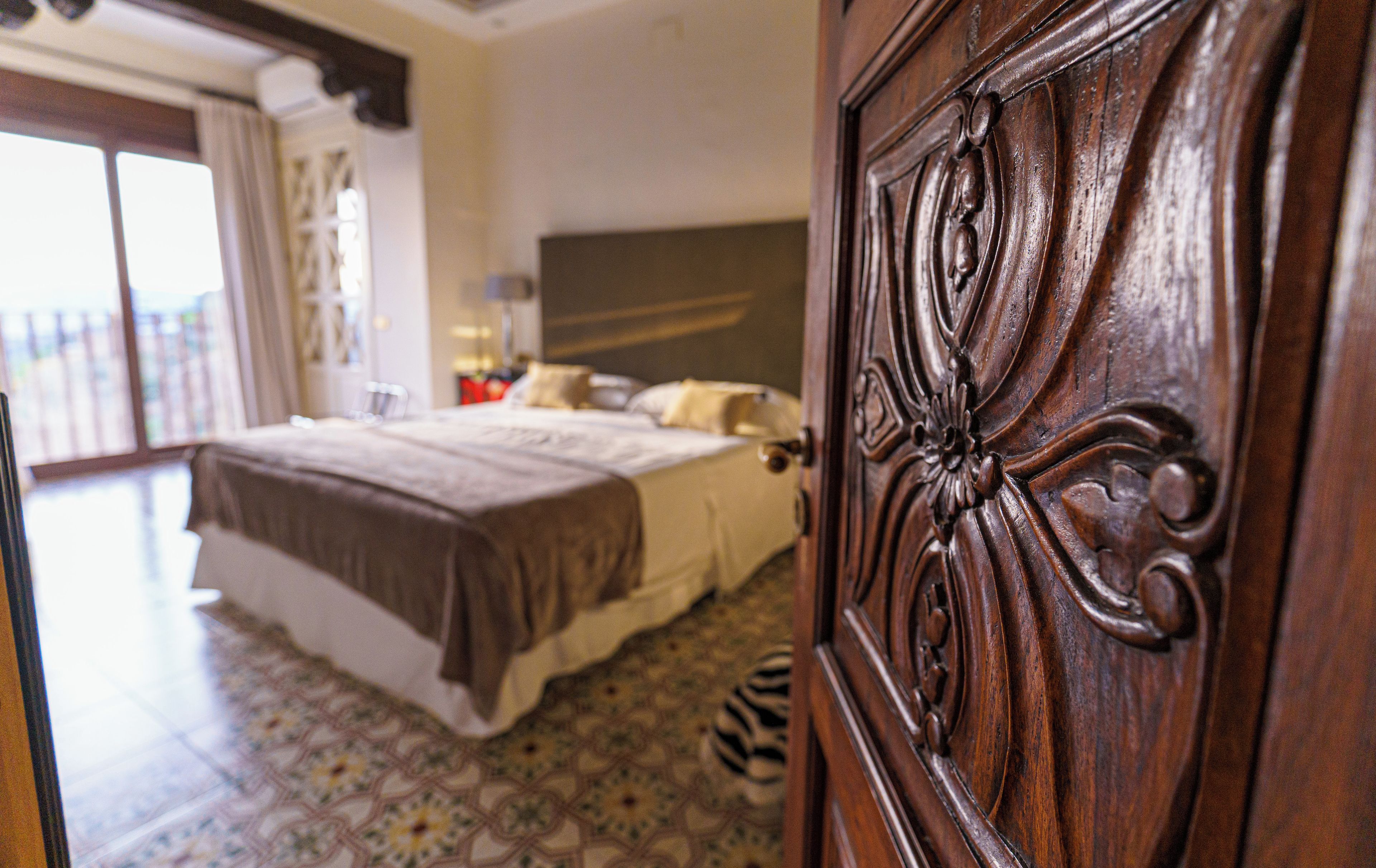 A hotel room with a bed, a zebra-patterned carpet, and a wooden door with intricate carvings.
