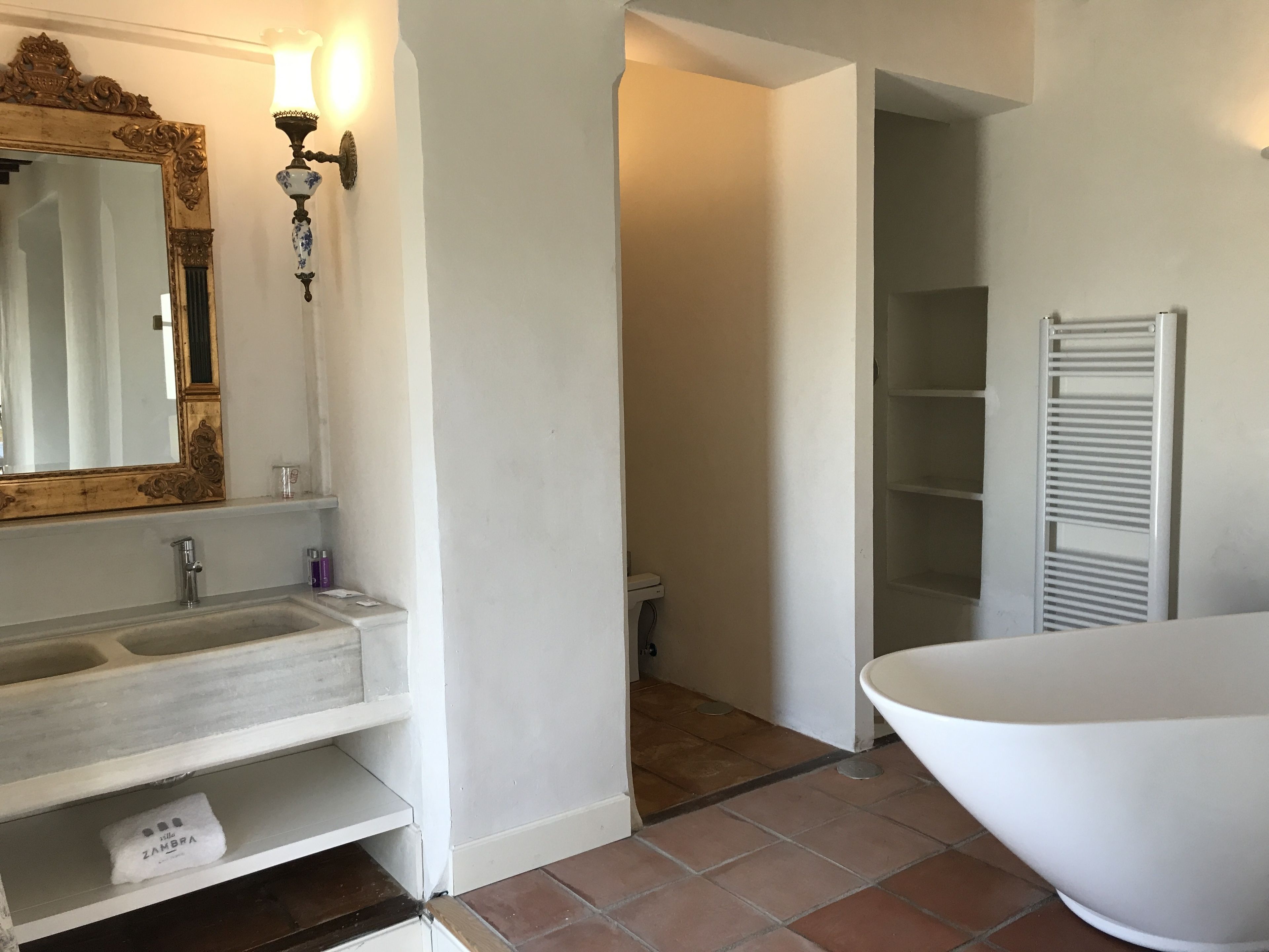 A bathroom with a large mirror, a sink, a bathtub, and a white towel on the shelf.