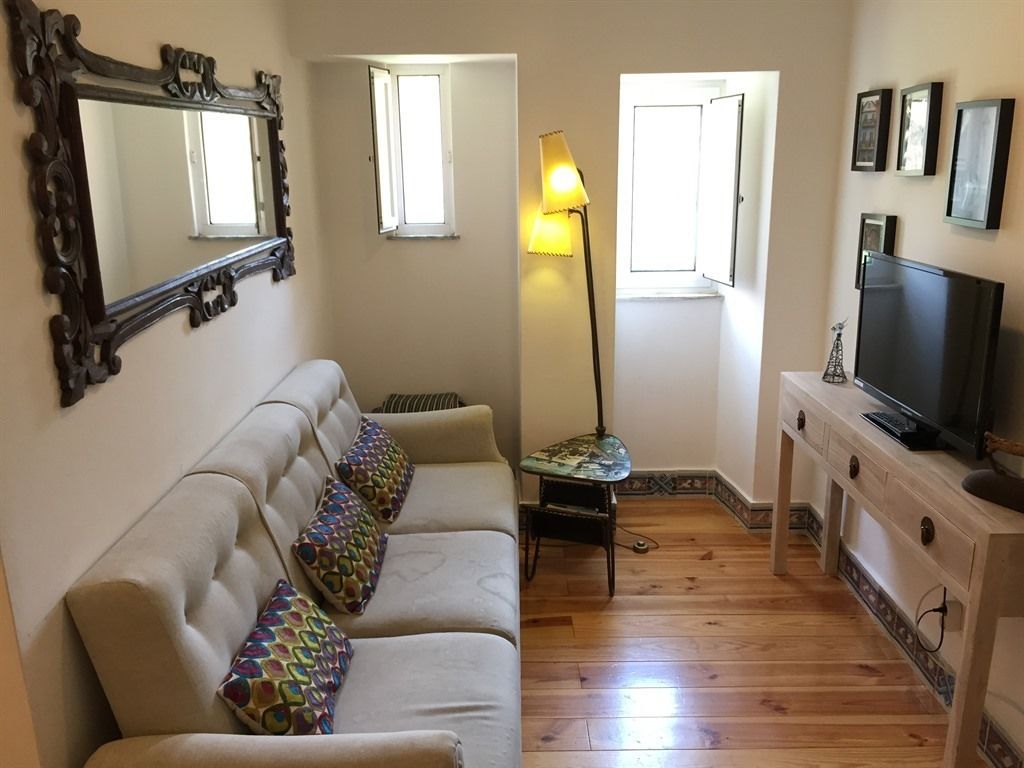 Een woonkamer met een bank, een lamp, een televisie en een spiegel.