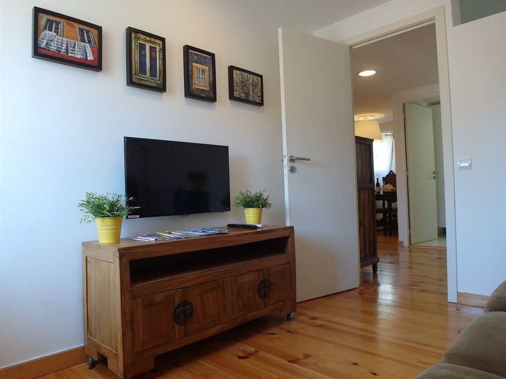 Un salon avec un meuble de rangement en bois pour l’équipement audiovisuel, un téléviseur à écran plat et trois œuvres d’art encadrées accrochées au mur.
