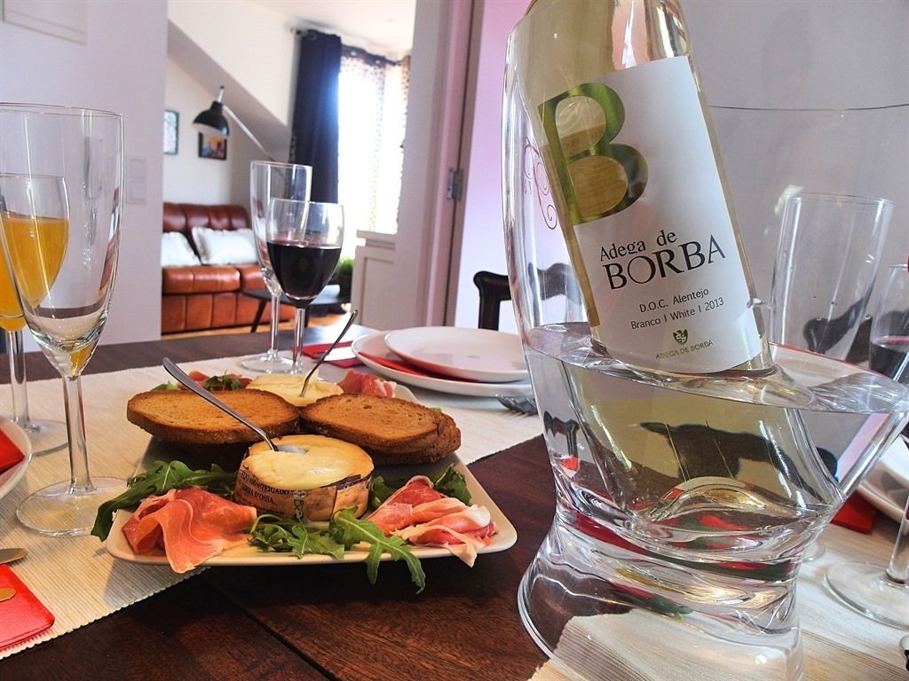 A dining table with a bottle of Borda wine, glasses, and a plate of food.