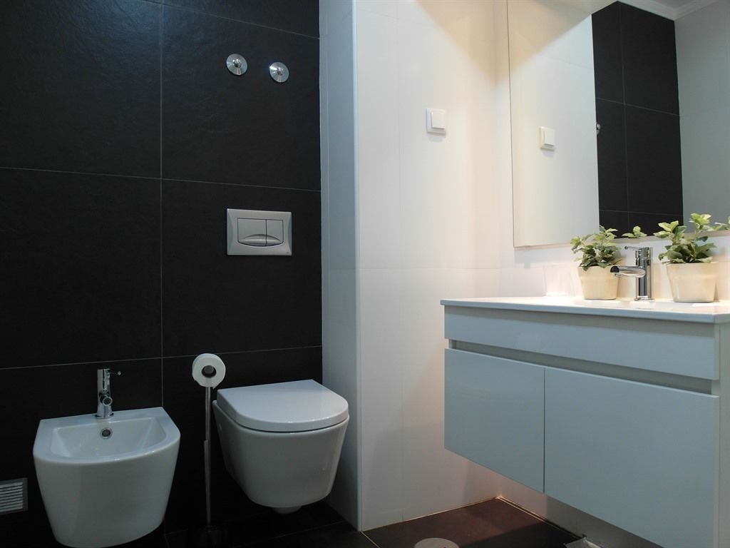A modern bathroom with a bidet, toilet, and a vanity with a mirror.