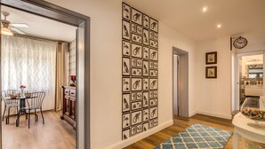 A hallway with a patterned wall, a dining area with a table and chairs, and a blue patterned rug on the floor. - AwesHome - Vintage Rooms (Pisa)