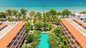A resort with a swimming pool surrounded by lush greenery, a beach with umbrellas, and a view of the ocean. - Avalon Beach Resort Pattaya (Pattaya)