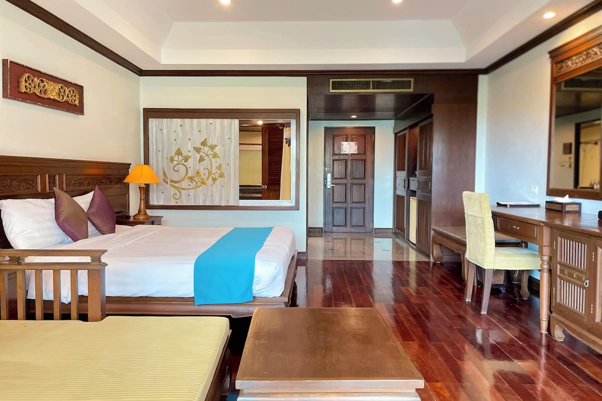 Una habitación de hotel con cama, mesita de noche, lámpara, silla, escritorio y espejo.