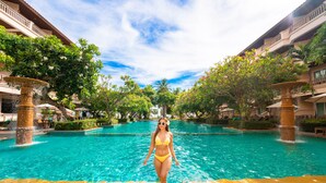 A pool area with a person standing in the water, surrounded by lush greenery and a clear sky. - Avalon Beach Resort Pattaya (Pattaya)