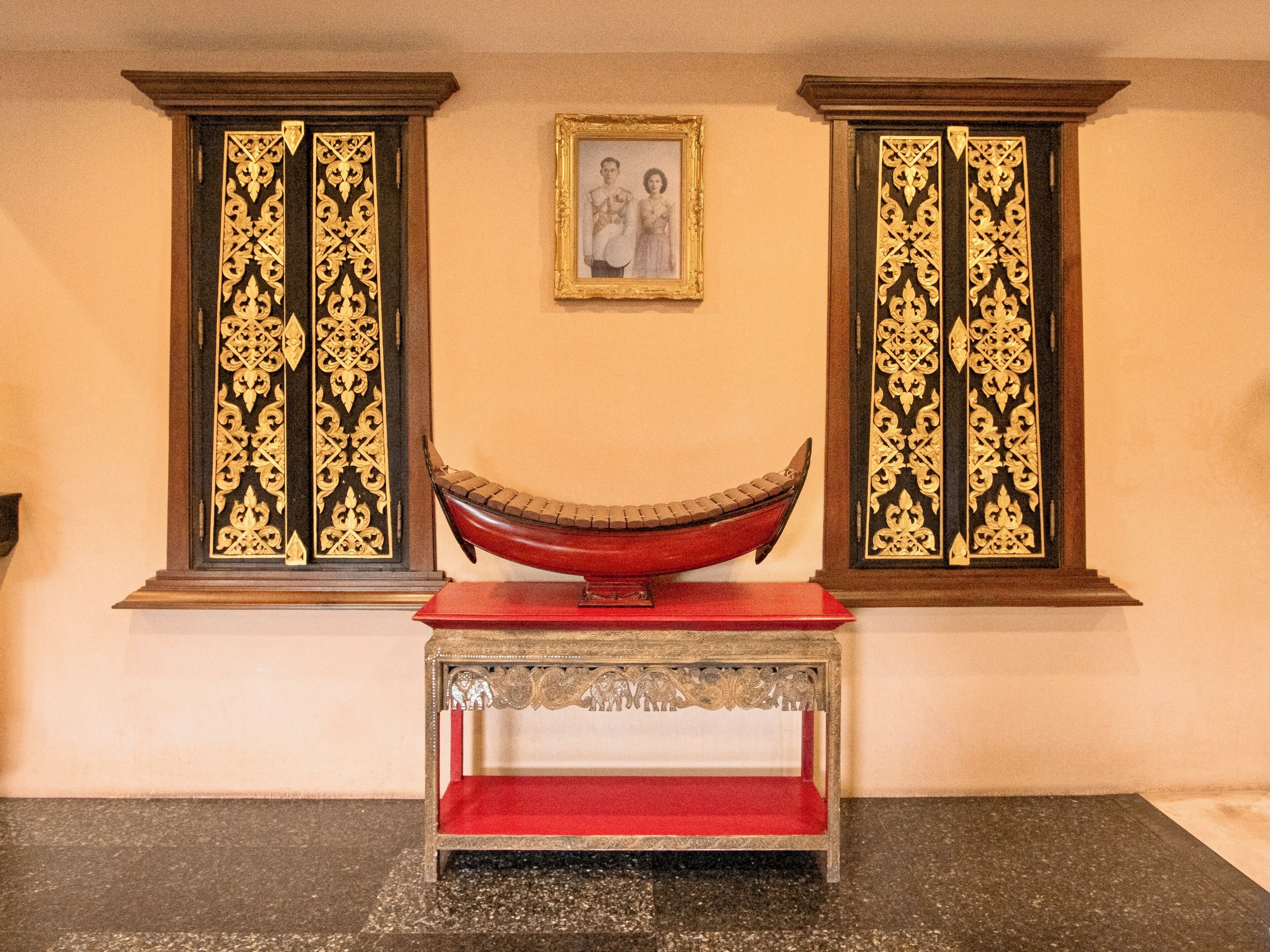 A room with a red bench, two ornate doors, and a framed picture on the wall.