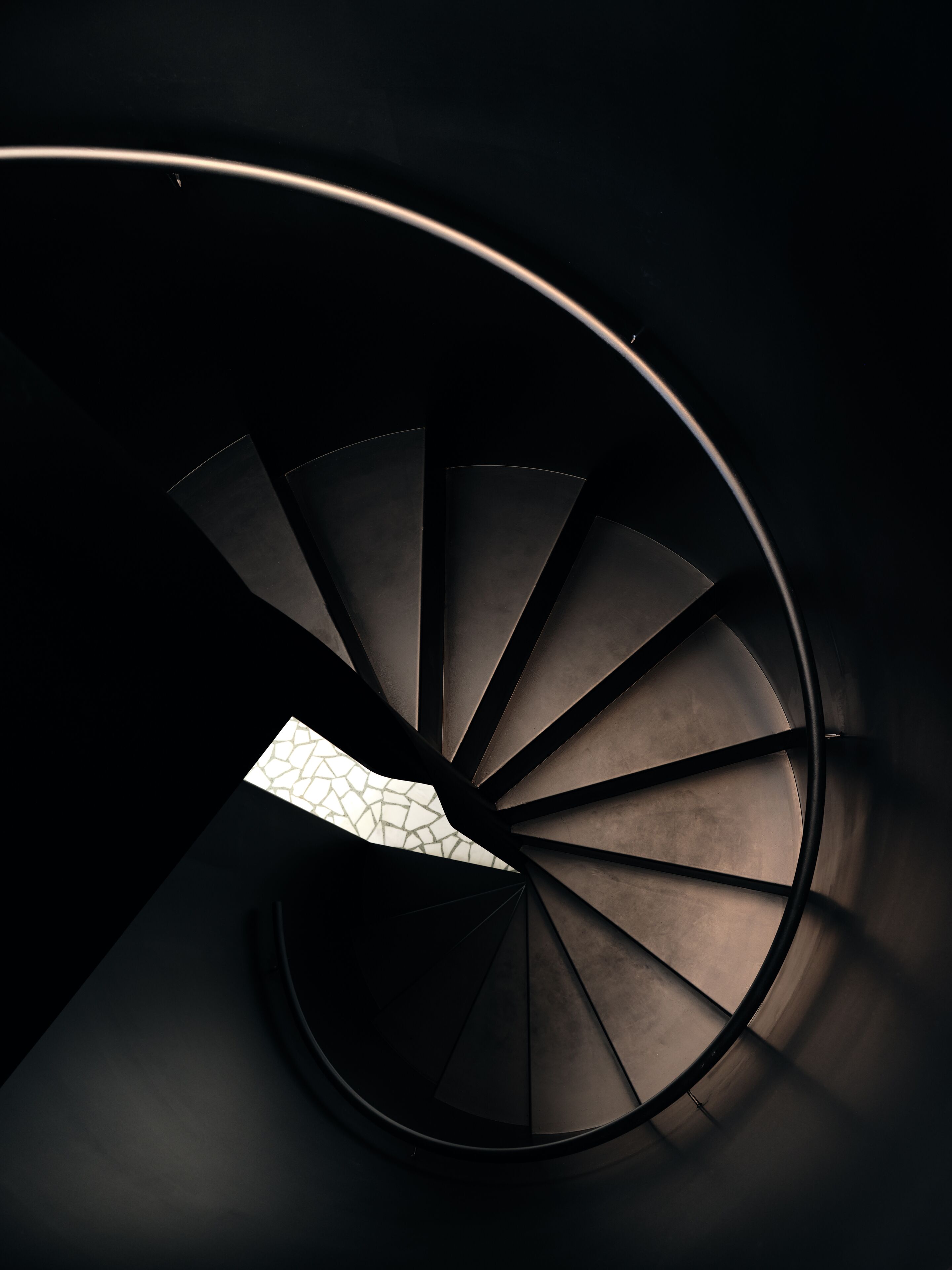 En spiraltrappe med en geometrisk lysarmatur øverst.