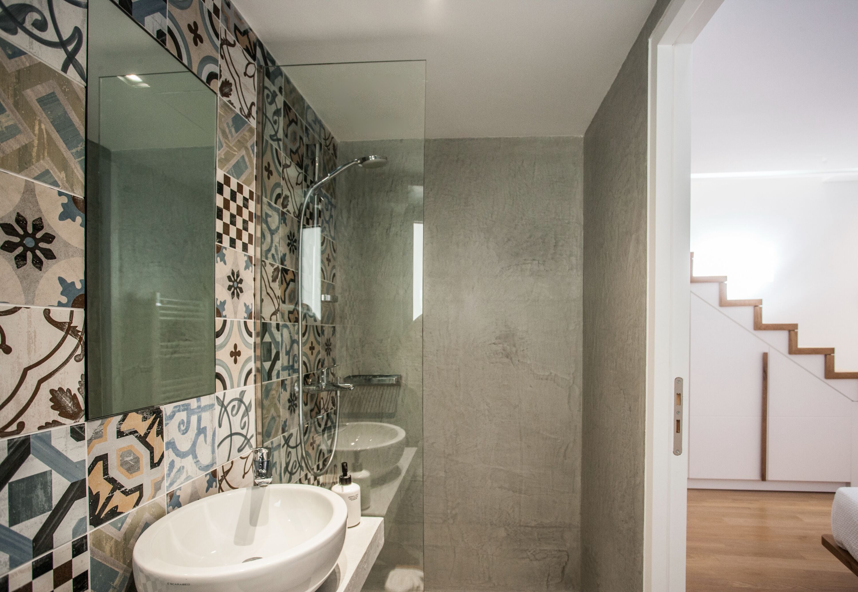 A bathroom with a large mirror, a sink, and a shower.