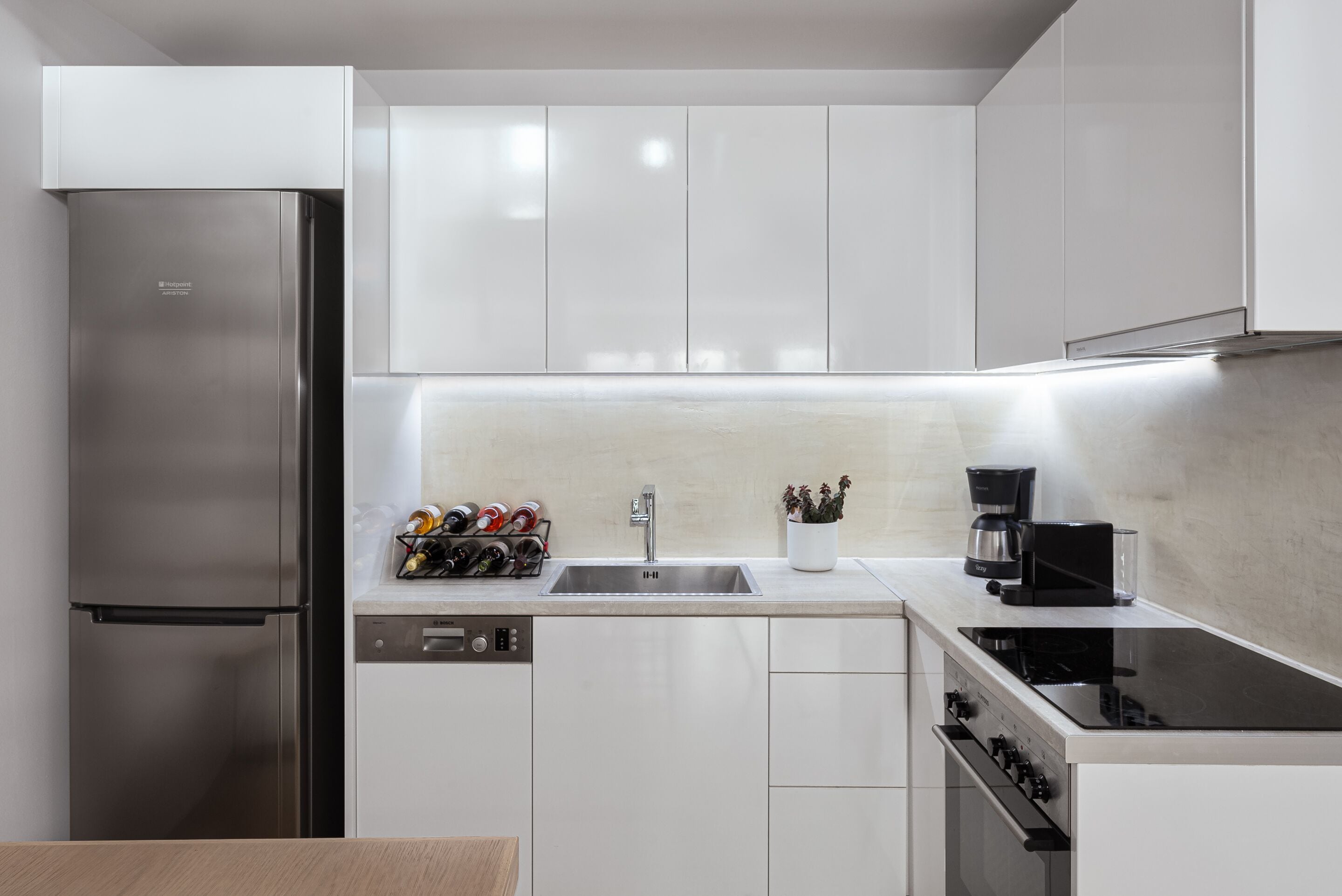 A modern kitchen with stainless steel appliances, white cabinetry, and a built-in dishwasher.