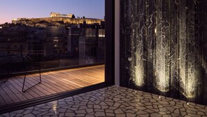 A modern interior with a large window overlooking a historic building at dusk. - Urban Stripes Athens (Athens)