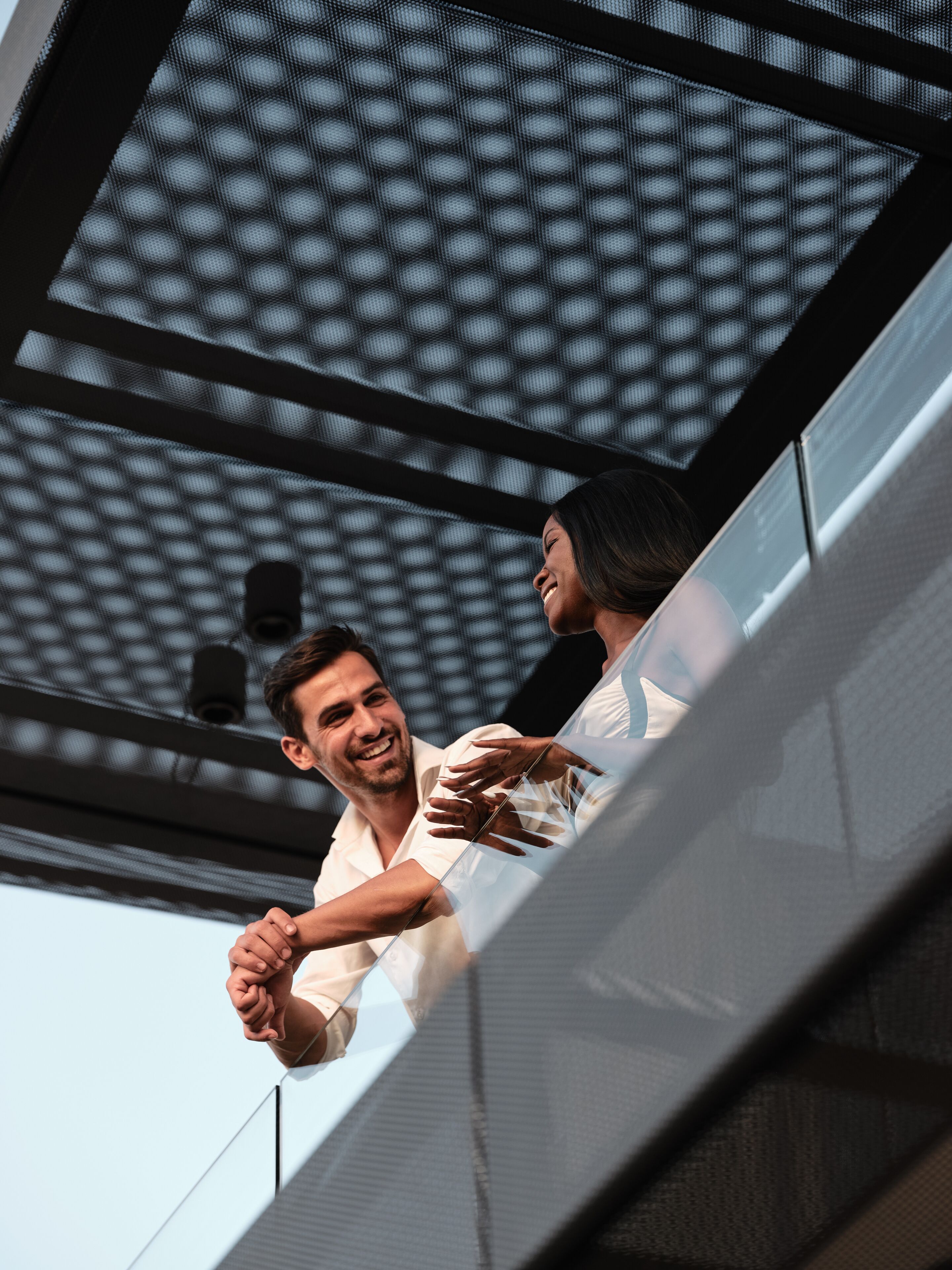 A man and a woman holding hands on an escalator with a patterned ceiling above.