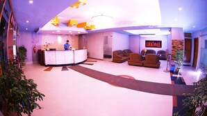 A modern lobby with a reception desk, seating area, and a large chandelier. - Britannia Hotel (Sylhet)