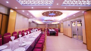 A banquet hall with long tables set for dining, a high ceiling with decorative lighting, and a modern architectural design. - Britannia Hotel (Sylhet)