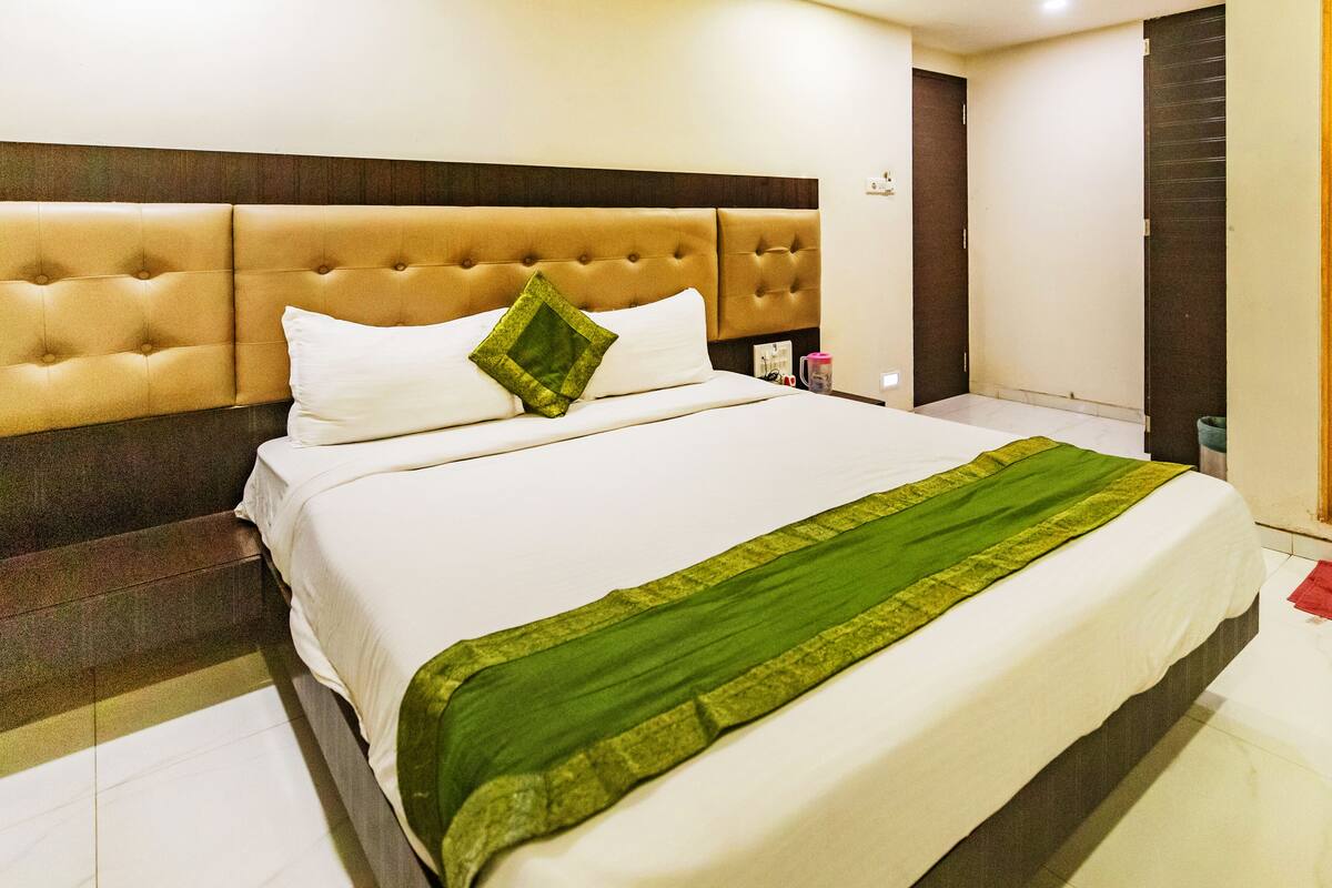 Quarto de hotel com uma cama grande, cabeceira e mesa de cabeceira.
