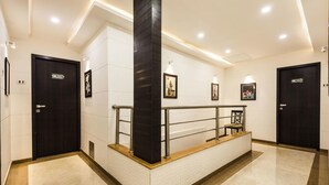 A modern hotel lobby with a reception desk, black doors, and framed artwork on the walls. - Hotel BKC Palace (Mumbai)