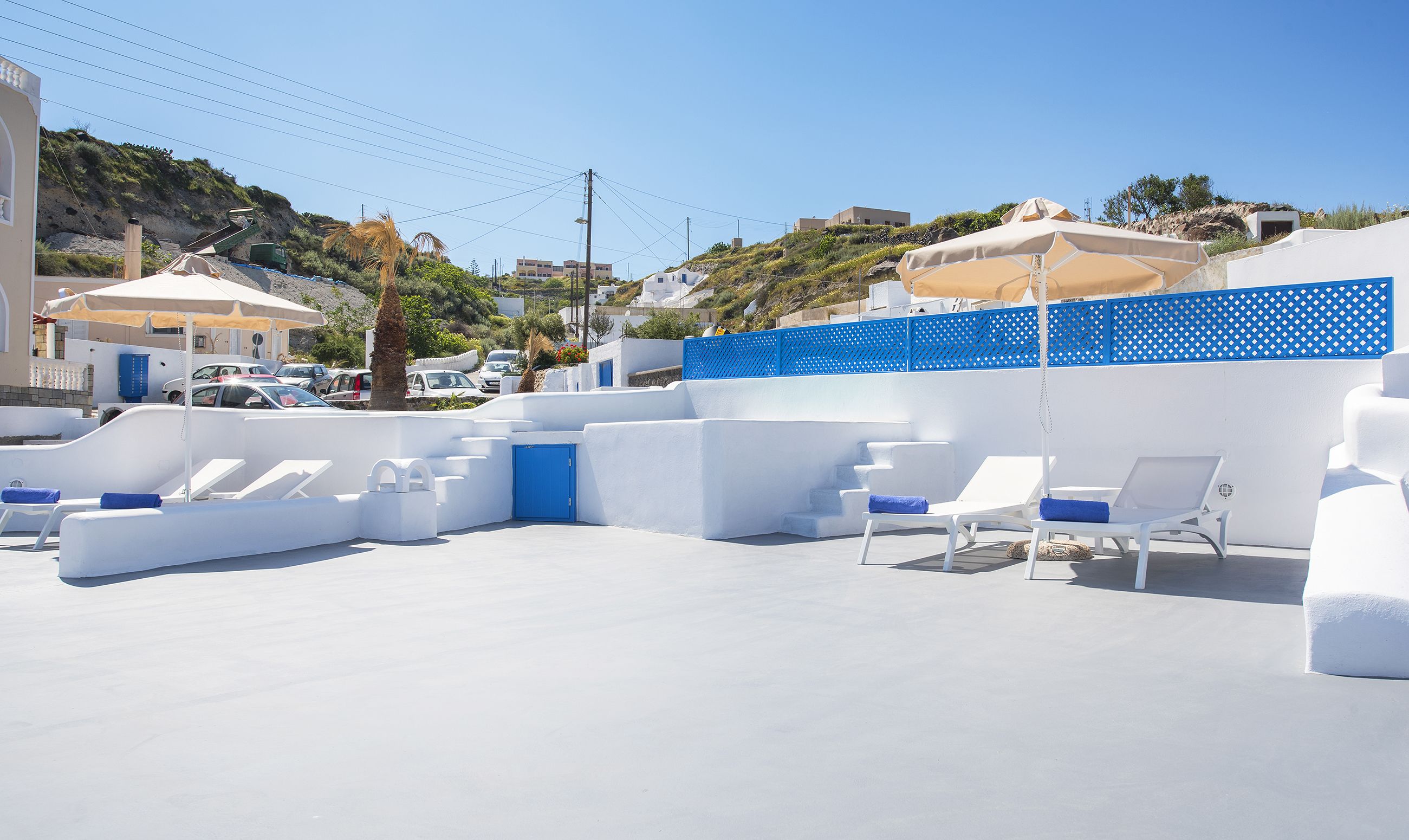 Un espacio al aire libre con paredes blancas, cojines azules y una puerta azul.