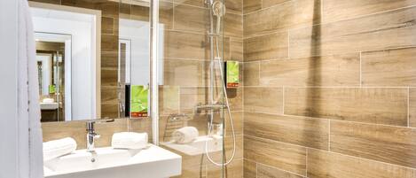 Un baño moderno con cabina de ducha de vidrio, un lavabo blanco y un espejo.