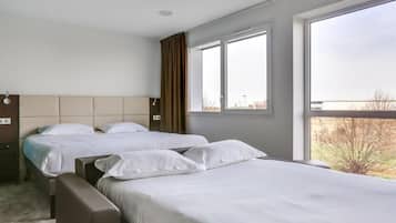 Ein Hotelzimmer mit zwei Betten, einem großen Fenster und Blick auf die Stadt.