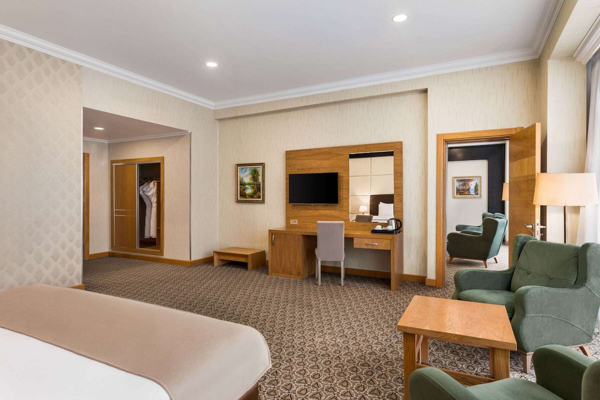 A hotel room with a bed, desk, chair, and a TV.