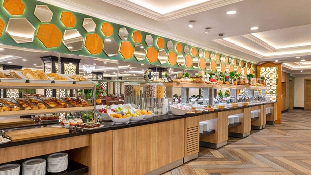 Buffet com diversos alimentos e uma parede decorativa com espelhos hexagonais.