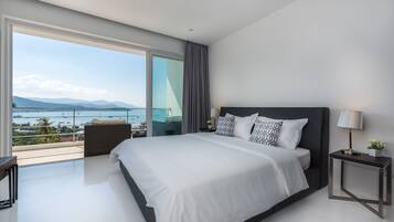 Una habitación de hotel moderna con una cama grande, una mesita de noche, vistas al mar y un balcón.