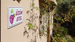 Um edifício com uma placa que diz “ÜZÜM OTEL” e uma ilustração de um cacho de uvas.