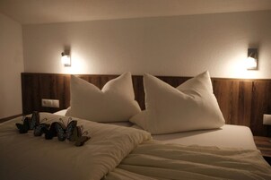 A hotel room with a bed, two wall-mounted lights, and a nightstand with a lamp.