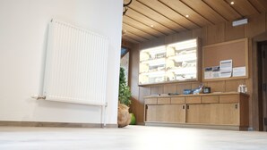 A reception area with a wooden reception desk, a bulletin board with notices, and a radiator on the wall. - Apart Felsenhof (Laengenfeld)