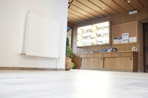 A reception area with a wooden reception desk, a bulletin board with notices, and a radiator on the wall.