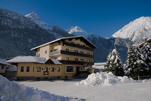 A multi-story hotel with balconies, set against a backdrop of snow-covered mountains.