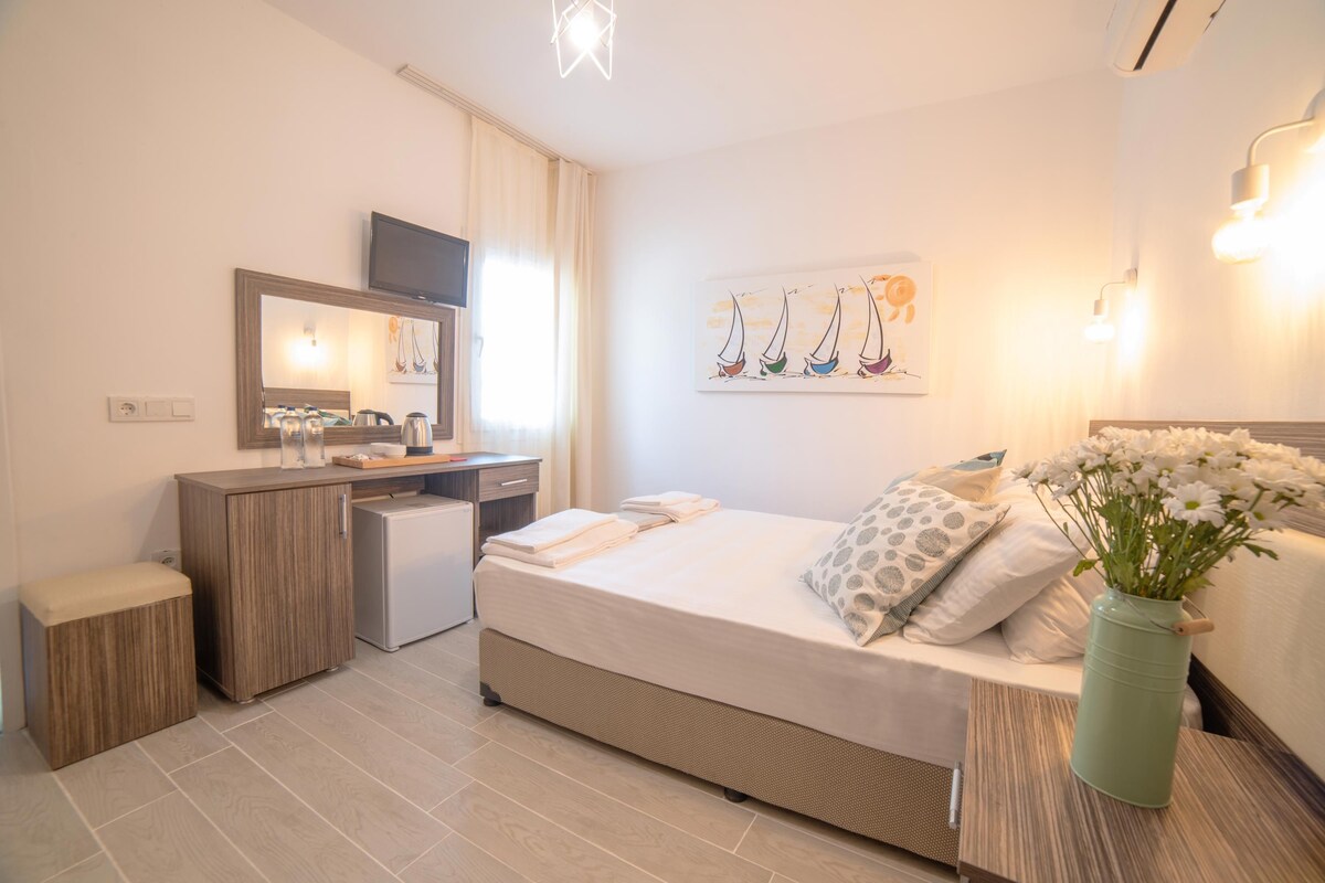 Ein modernes Hotelzimmer mit Bett, Nachttisch und einer kleinen Schreibtischzeile.